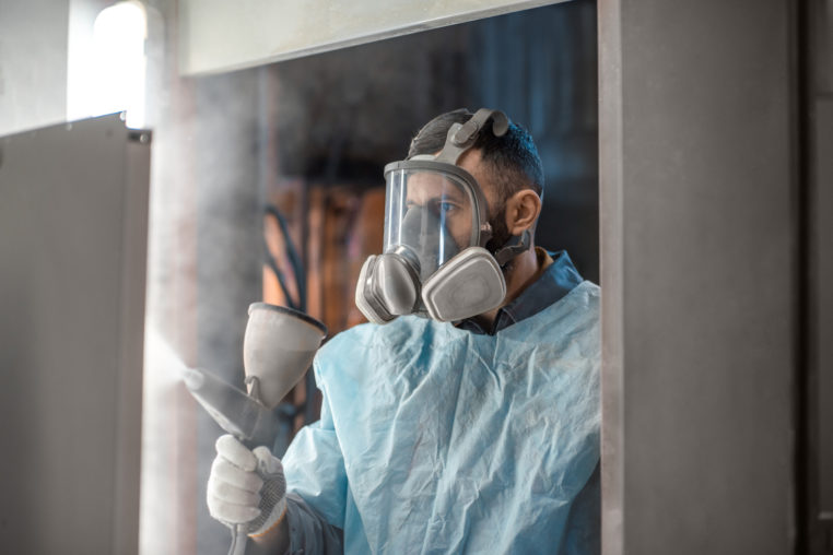 man in protective wear powder coating metal