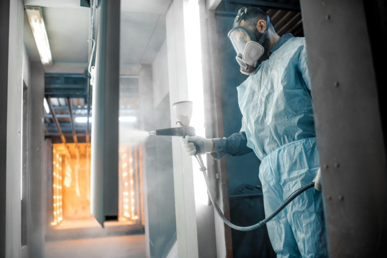 man in protective wear performing powder coating