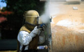 worker removing paint by air pressure sand blasting